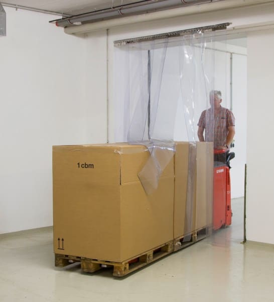 Mann fährt Elektrohubwagen mit beladenen Paletten  durch den PVC Streifenvorhang