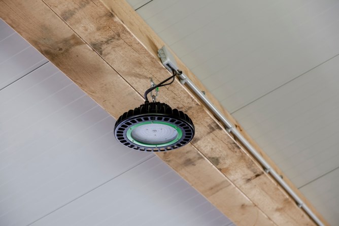 Der ausgeschaltete 100 W Kerbl LED Hallenstrahler  an der Decke an einem Holzbalken montiert