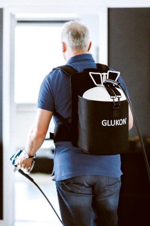 Rückansicht eines Mannes mit dem Rucksack für Glukon Sprühkleber auf dem Rücken